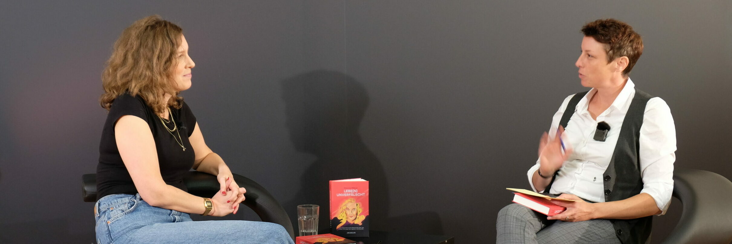 Melanie Möbus und Tanja Gratzer beim Gespräch. Dazwischen ein Tisch mit einem Exemplar von "Lebe(n) unverfälscht"