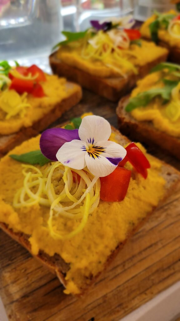 Brötchen mit gelbem Aufstrich und Stiefmütterchen als Deko,